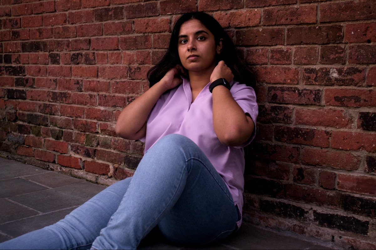 Arya sitting leaning against a brick wall